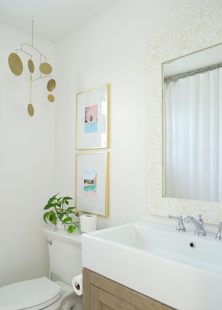 White bathroom with inlay mirror gold picture frames and brass mobile