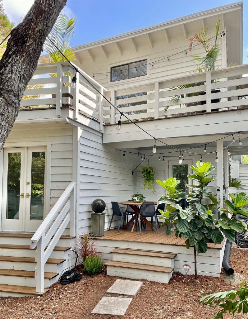 Full View of House With Kitchen Porch On First Floor With Plants And String Lights