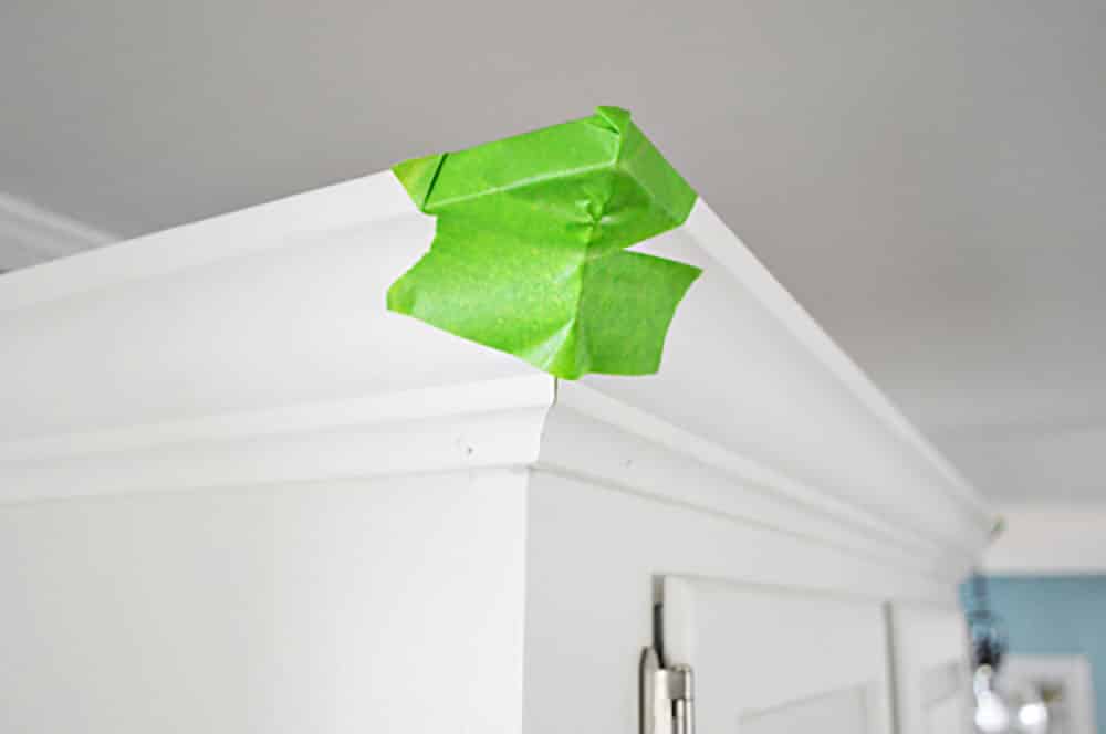 Green painters tape on the corner of kitchen crown molding while glue dries