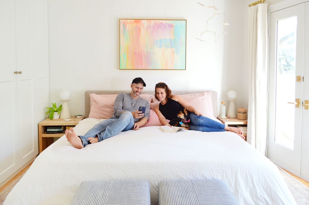 John And Sherry Looking At Phone With Dog On King Size Bed