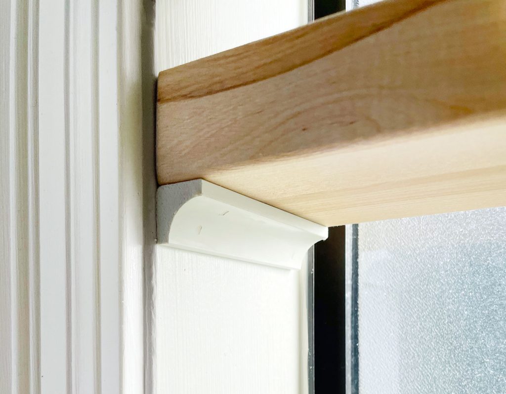 Close-up of a butcher block shelf supported by cove molding in a bathroom window