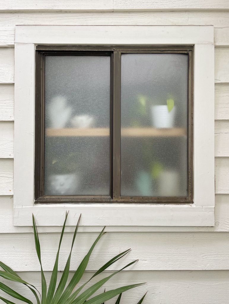 Frosted Bathroom Window Seen From Outside With Wooden Shelf