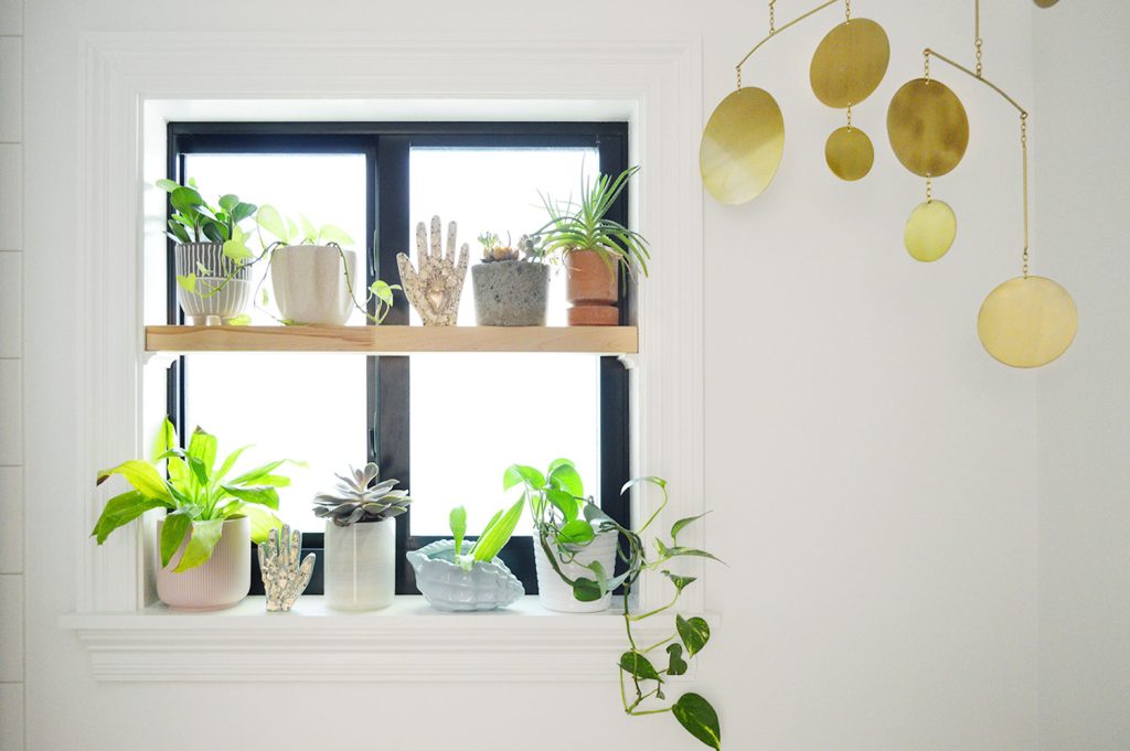 Window plant shelf with gold mobile in bathroom
