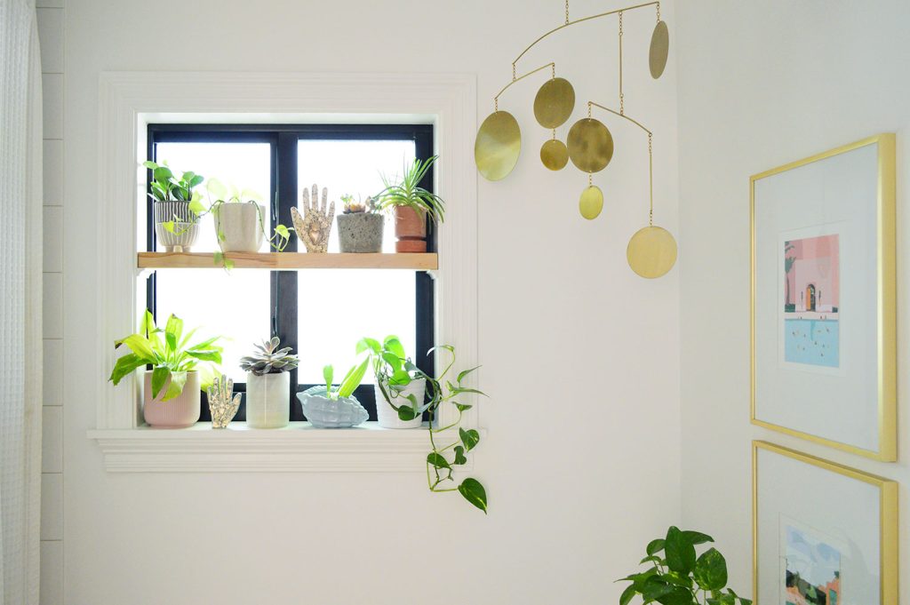 Wood window plant shelf in bathroom with gold mobile