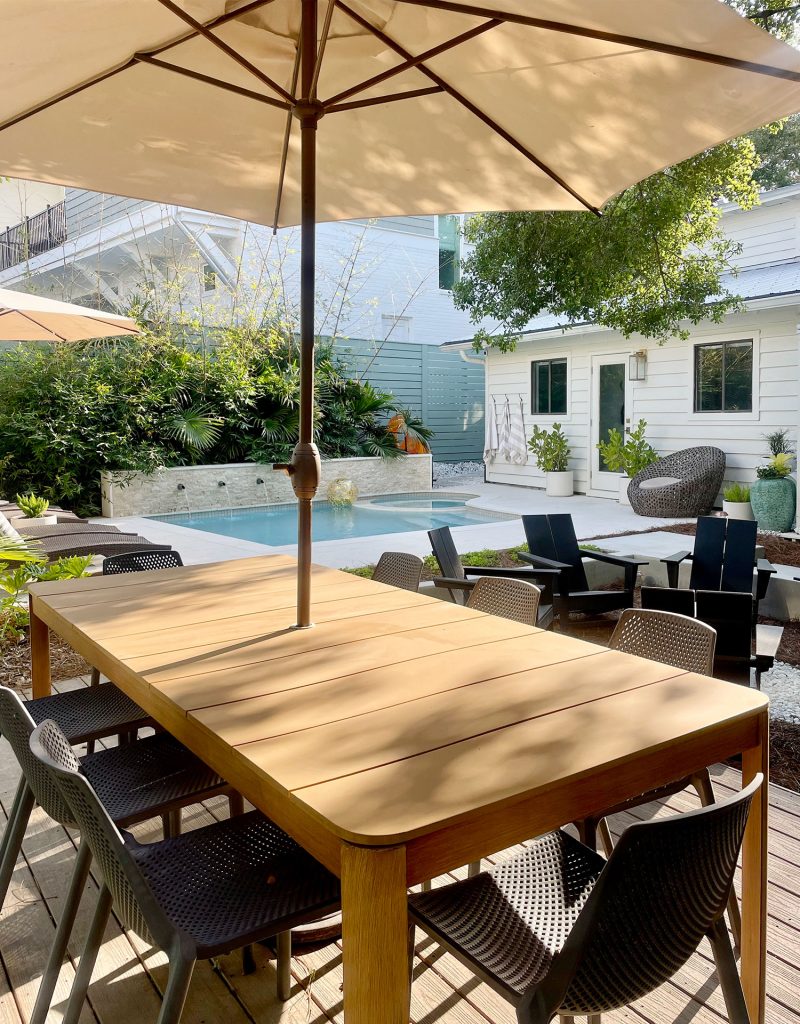 Metal dining table with umbrella in backyard pool area