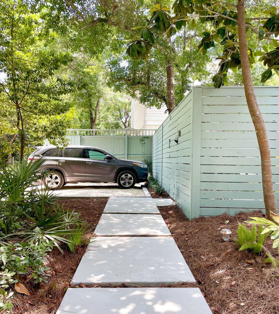 Gray SUV parked in gravel driveway parking spot with concrete walkway sidewalk