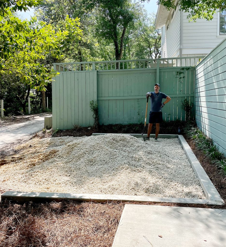 John with shovel spreading pile of bahama rock in driveway parking spot
