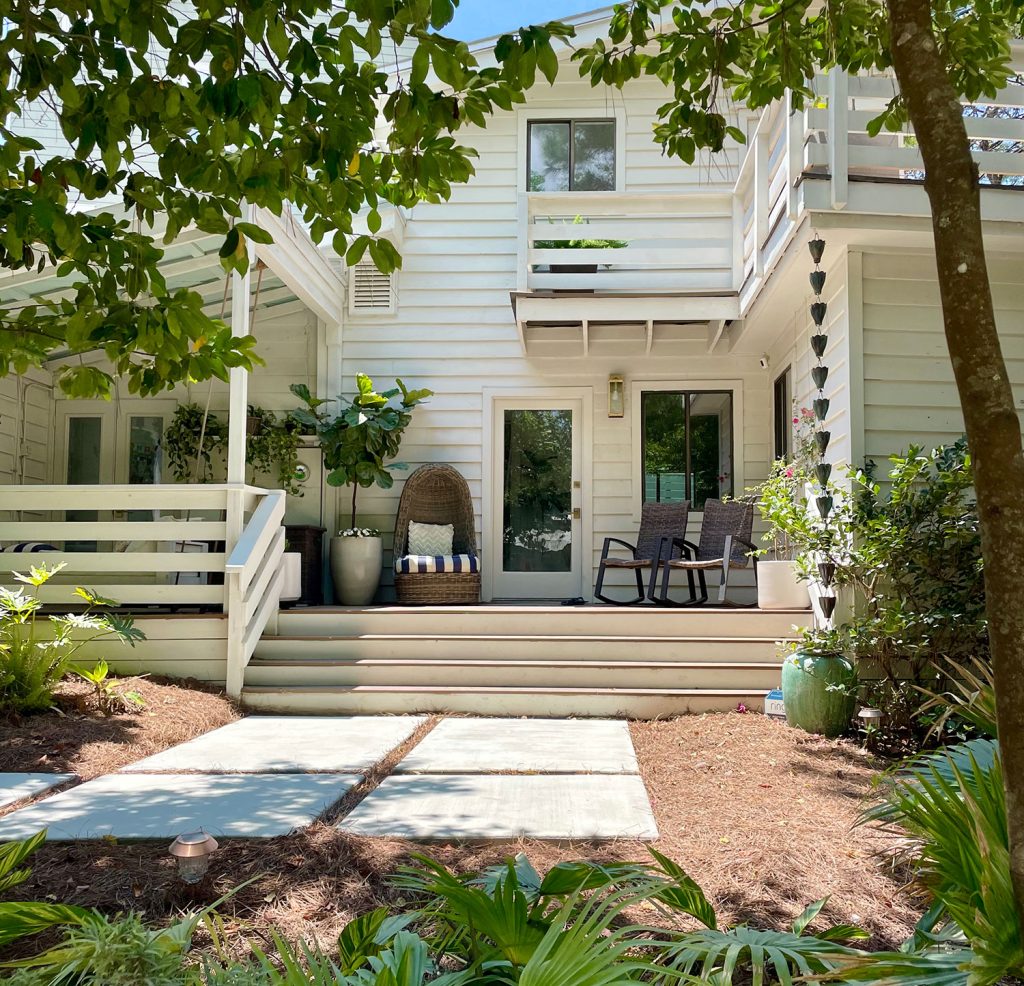 Front Of White Modern House With Lots of Greenery With Large Concrete Walkway