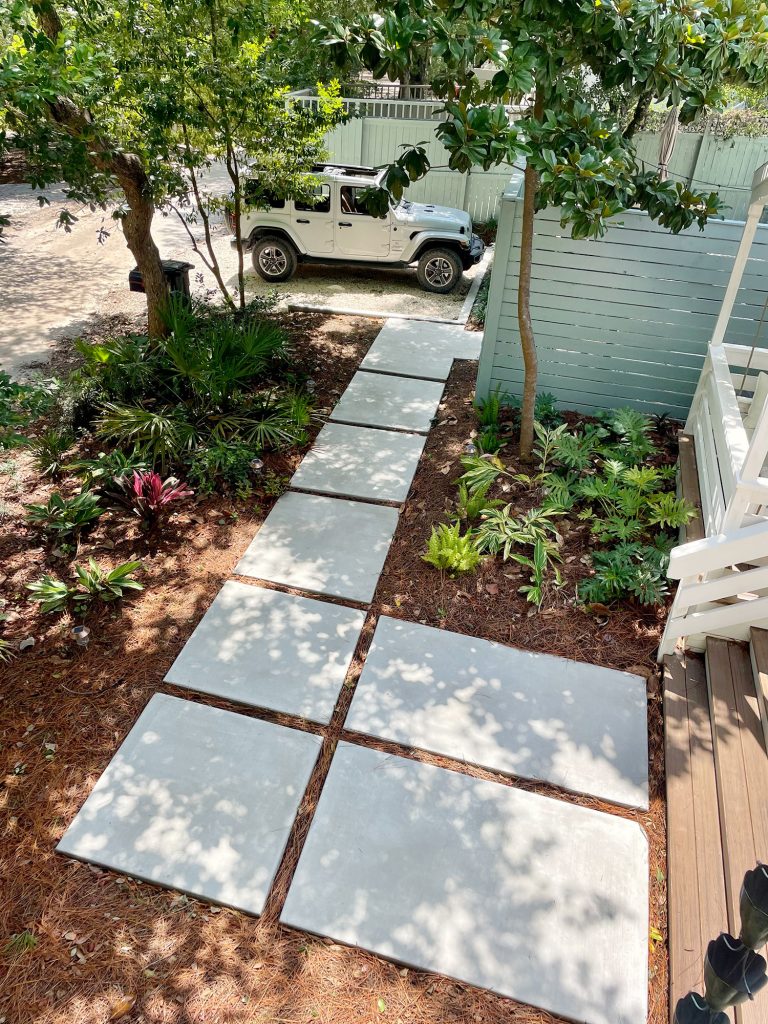 Large paver walkway leading to Jeep parked in gravel driveway