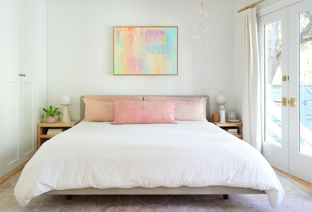 White King Bed With Pink Pillows And Bright Colorful Painting