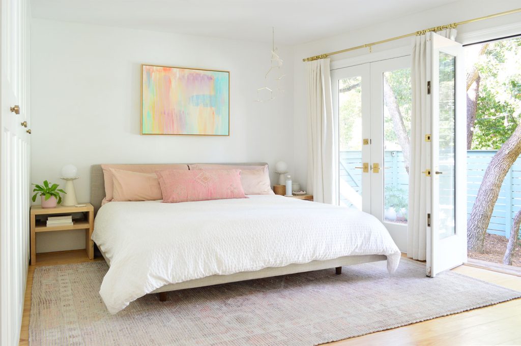 Bright Beachy Bedroom With Pink Pillows And Open French Door Overlooking Yard