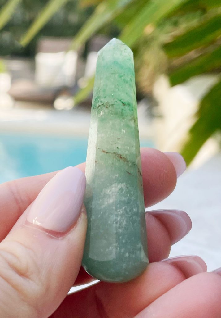 Hand holding green aventurine crystal point