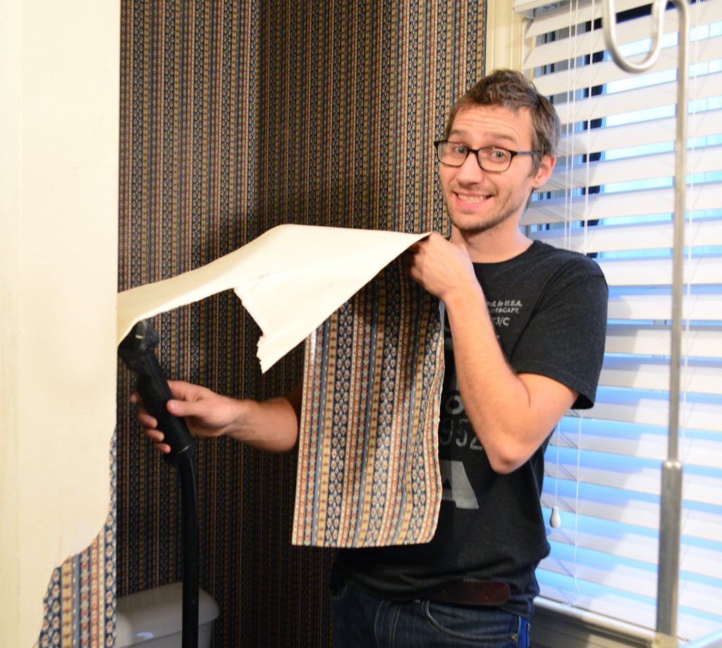 John using steamer to remove wallpaper in bathroom