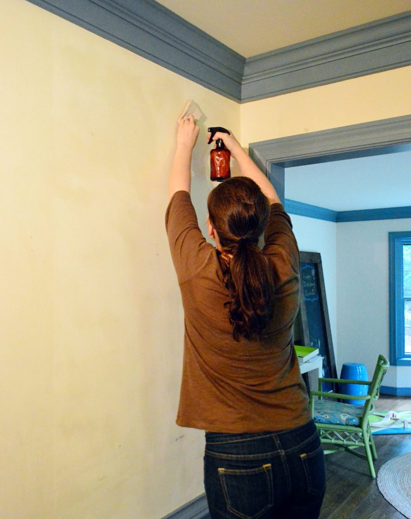 Sherry spraying sections of wall to remove wallpaper glue