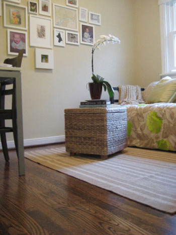 clean hardwood floor with dash & albert striped rug and woven wicker ottoman with orchid