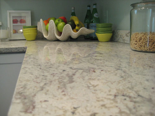 clean kitchen light granite countertop with fruit bowl in background