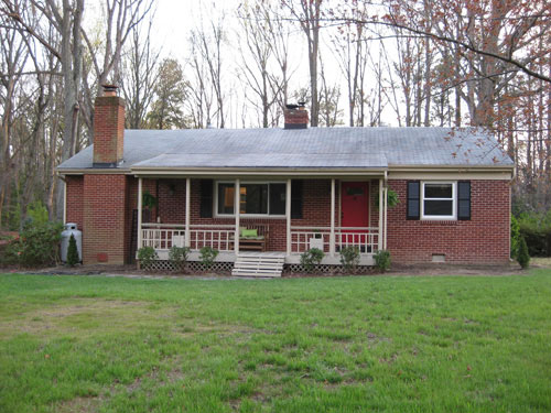 Small brick ranch home with propane tank in the corner