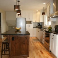 A Kitchen With A Dark Wood Island And White Cabinets