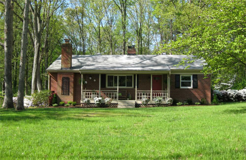 After photo of brick ranch with disguised utility boxes and propane tank and blooming flowers