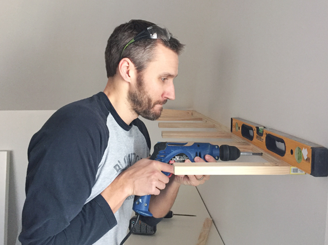 attaching brace piece for white floating shelves using a power drill driver and level