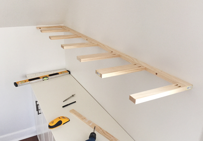 Brace piece of DIY thin wood floating shelves hung on a wall using 1x3 and 1x2 pine boards