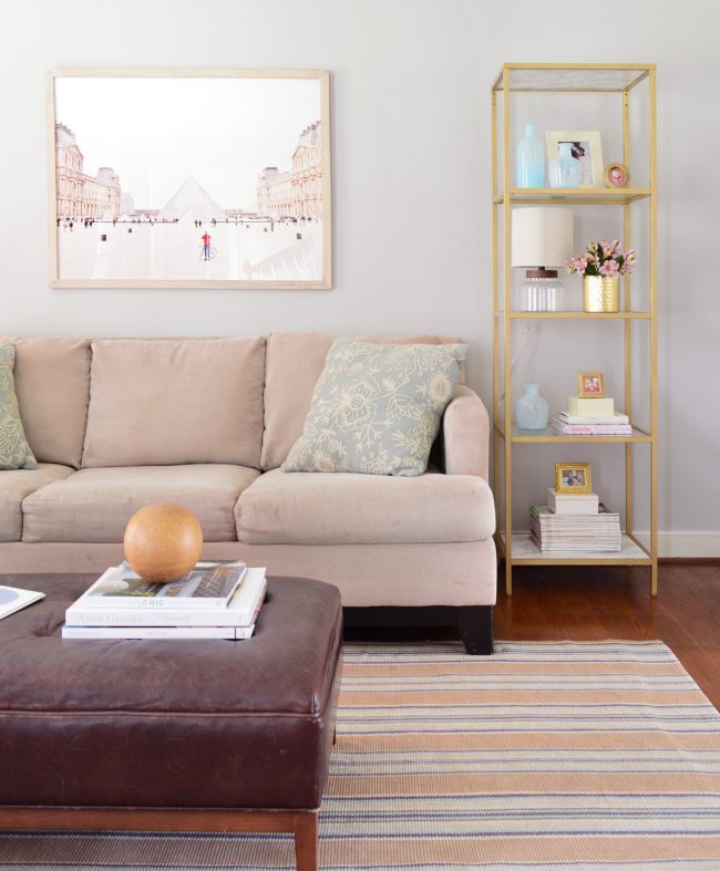 neutral living room with gold shelves and large art