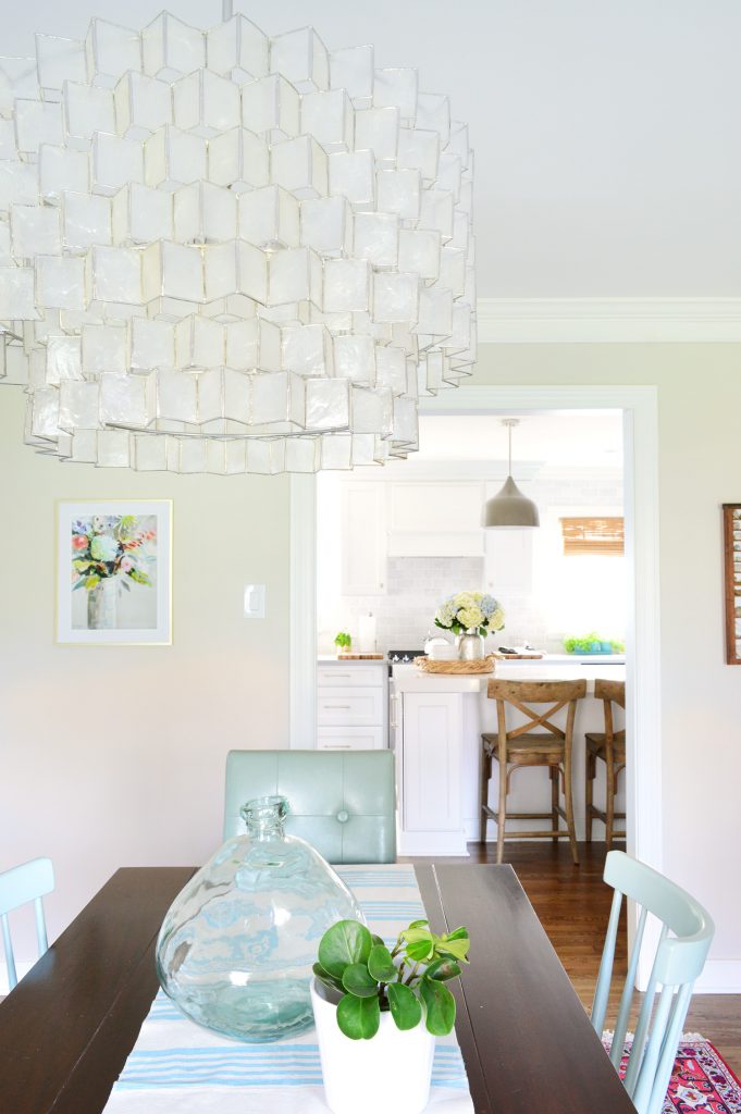 Capiz light fixture in dining room with large glass vase