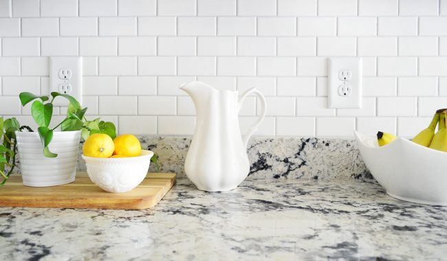 detalhe do backsplash da cozinha em azulejo de metrô branco com limões e jarro