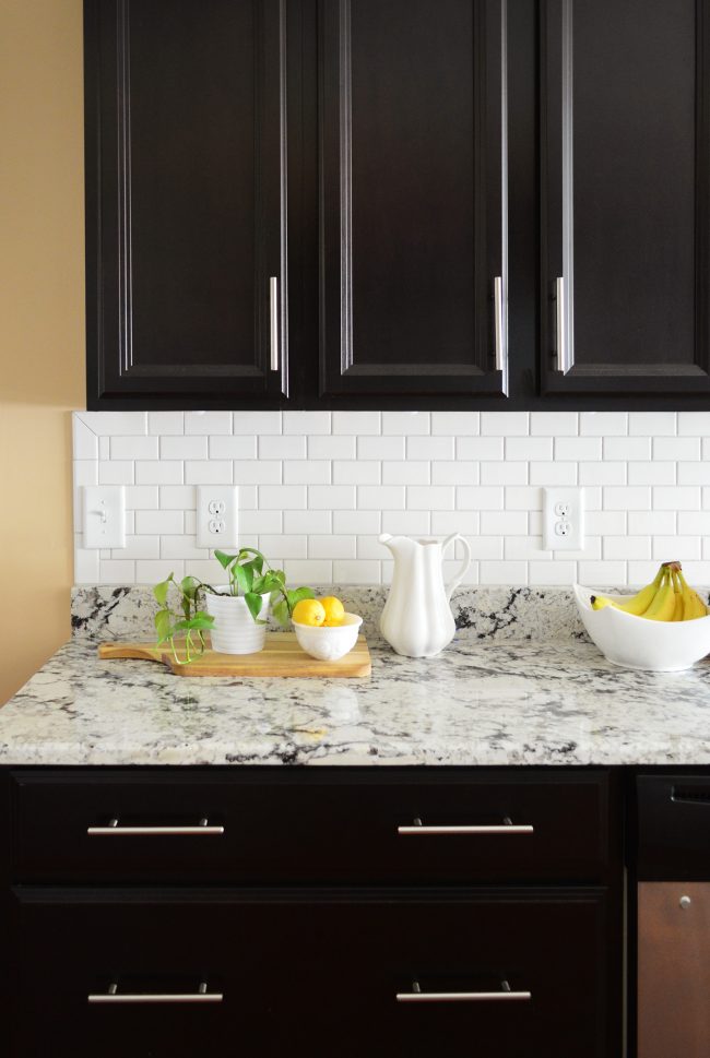 white subway tile sheet backsplash with black cabinetry