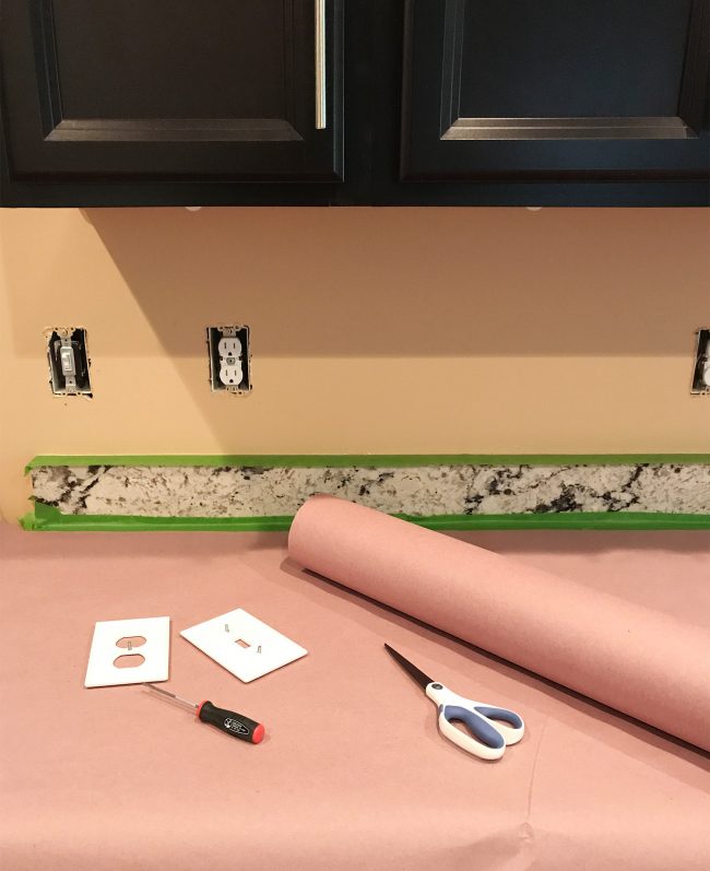 kitchen prepared for tiling with outlet covers removed and counters protected