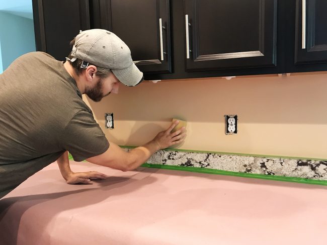 John lixando a parede do backsplash em preparação para a instalação do azulejo