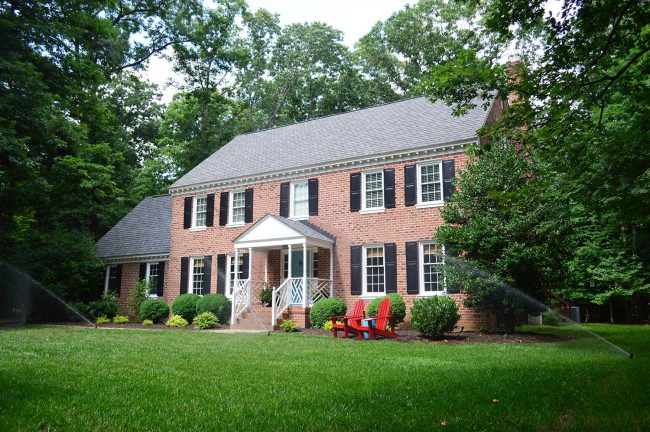 irrigation system watering lawn of brick colonial home