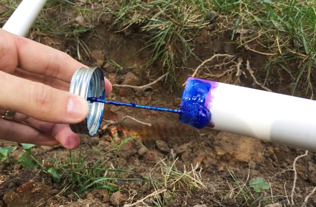 applying blue cement to connect irrigation system pipes