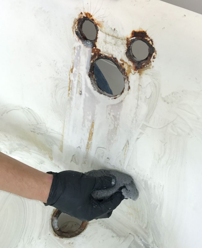 Wiping stains in clawfoot tub with steel wool sponge