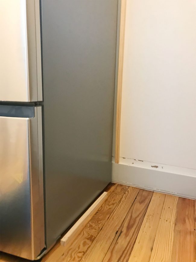 thing pieces of wood installed near fridge on wall and floor