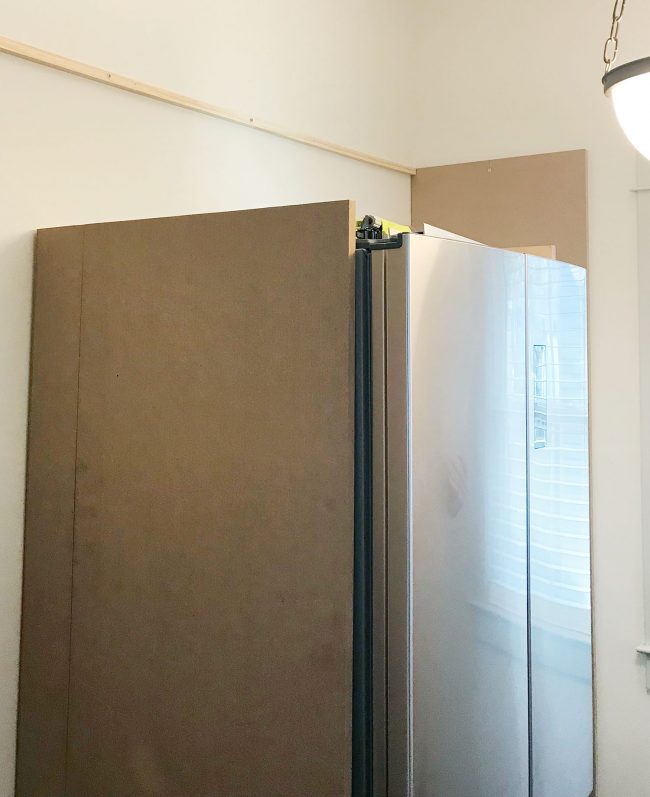 large MDF pieces added vertically against fridge in pantry