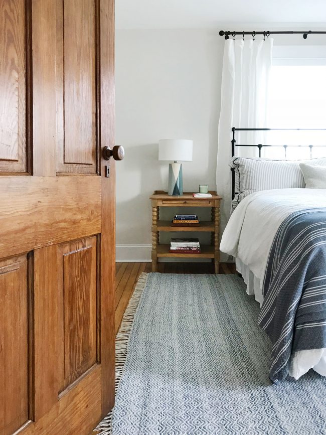 bed in front of window with original pine door