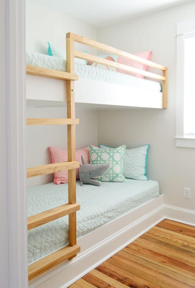 diy built in beds with raw wood railing and ladder in a small room