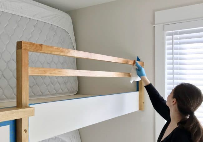 Sherry applying stain to bunk bed railing for raw wood look