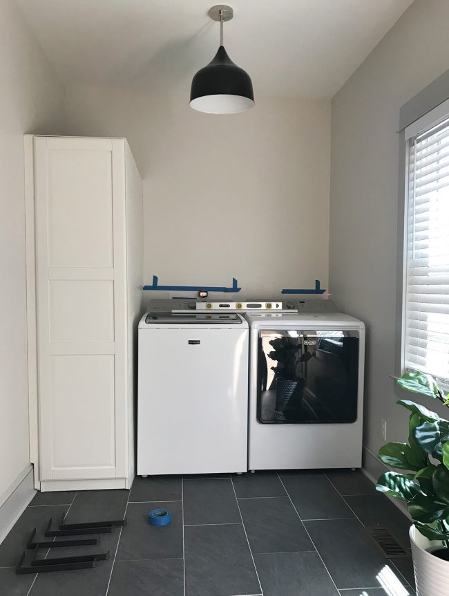 ikea pax wardrobe placed next to top loading washer and dryer in laundry room