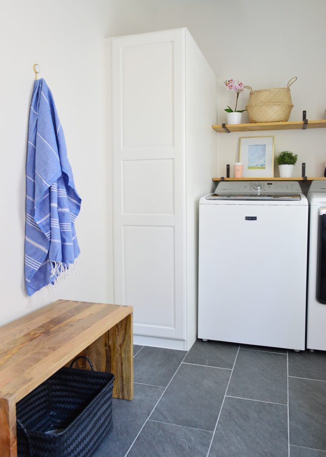 wood bench in front of laundry room storage with towel hook