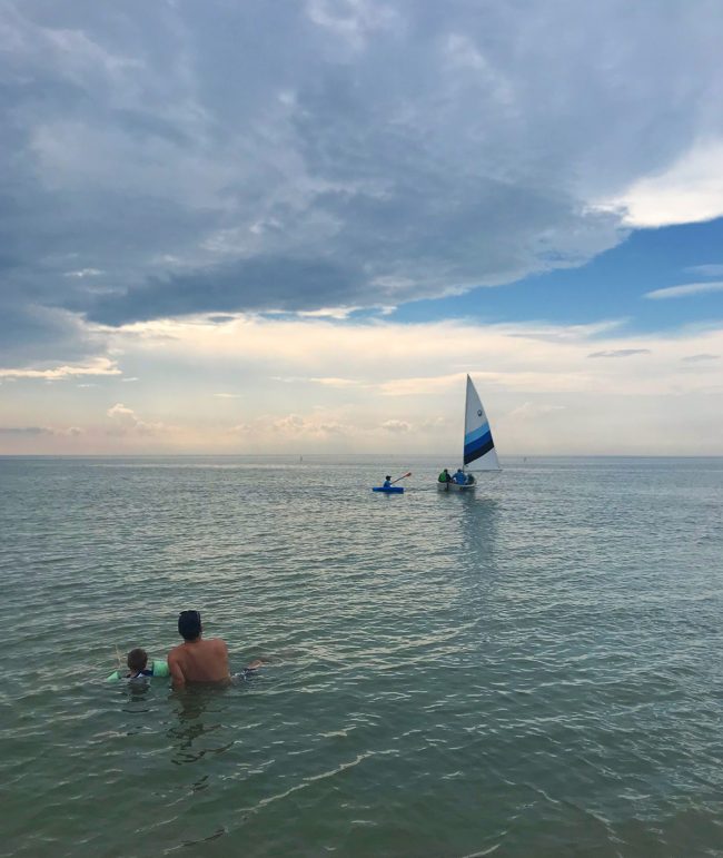 people sitting in water watching sailboat on cape charles beach