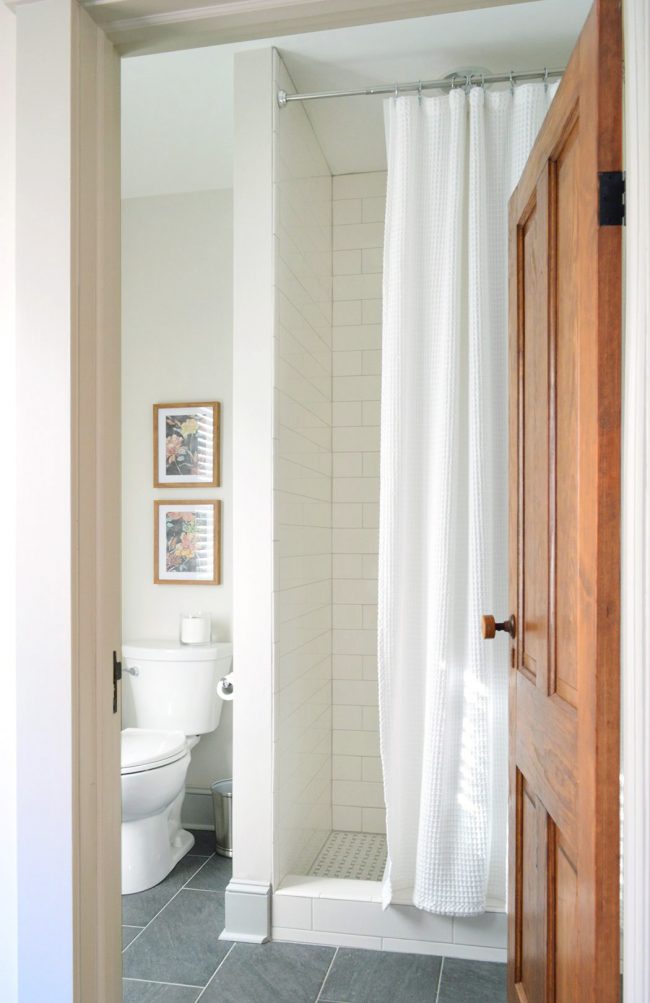 View Into Finished Downstairs Bathroom With Subway Tile Shower And Reclaimed Wood Doors