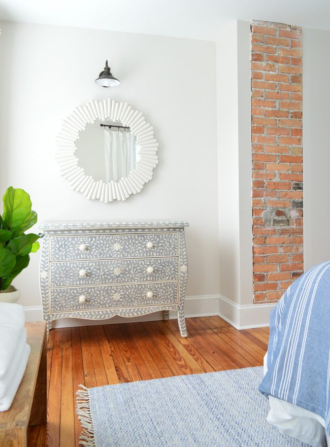 After Photo Of Beach House Front Bedroom With Exposed Brick Fireplace And Blue Inlay Dresser