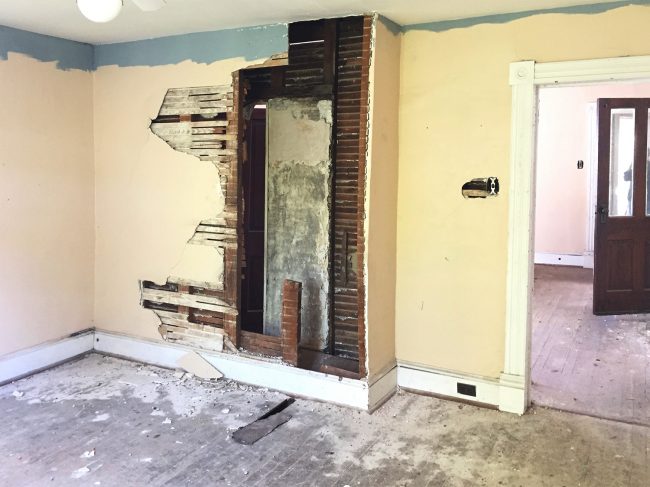 Before Photo Of Back Bedroom With Crumbling Walls and Exposed Chimney