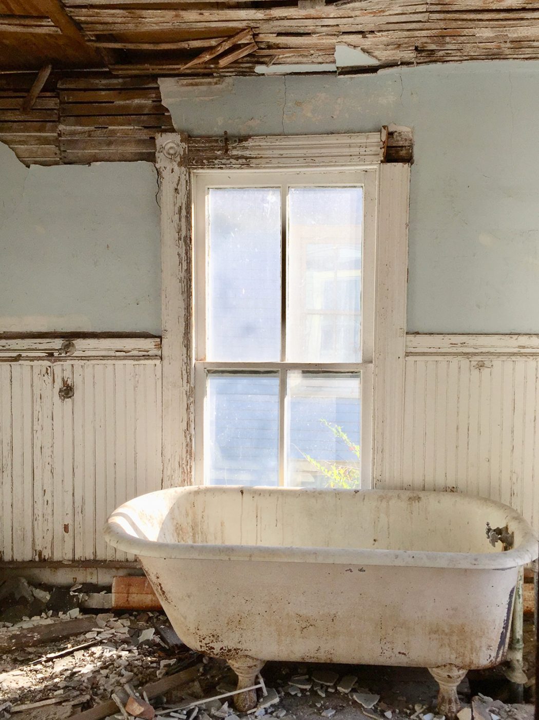 Before photo of beach house bathroom with crumbling walls and dirty tub