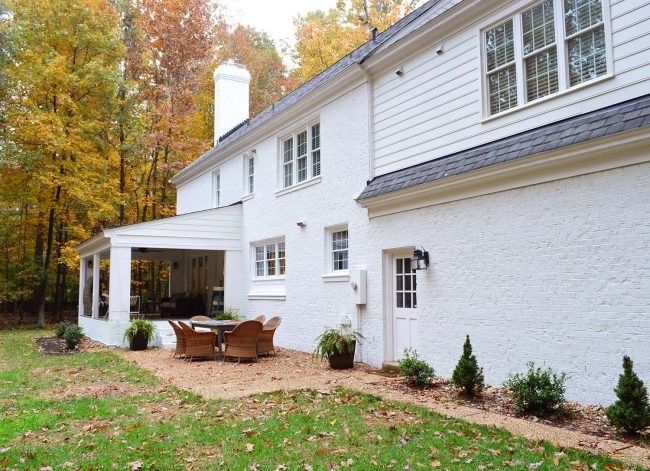 after photo of back of a brick house painted white with some siding