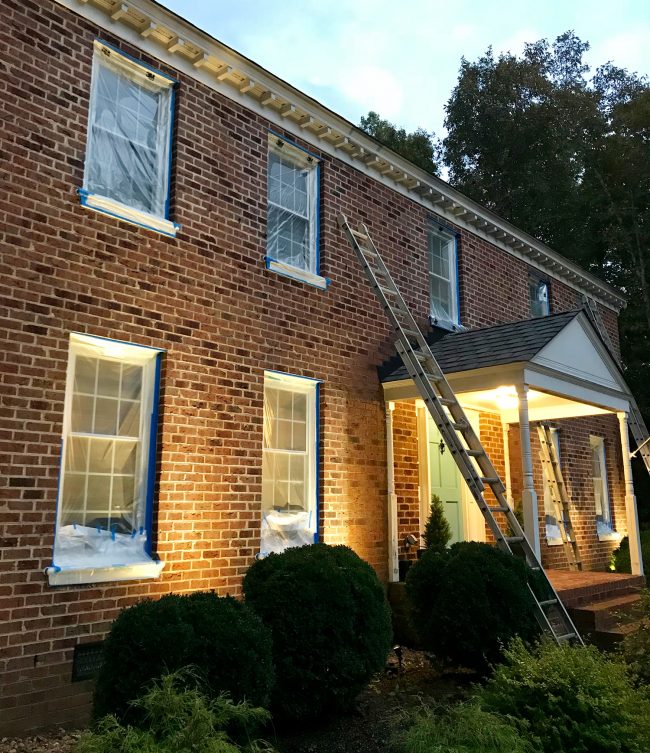 brick house prepped for painting with windows taped up