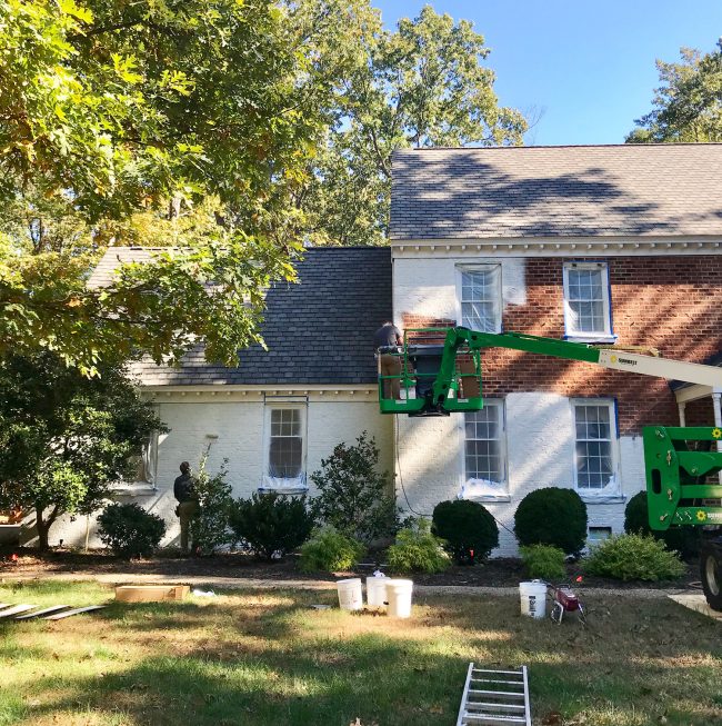 painters working on painting a brick house white