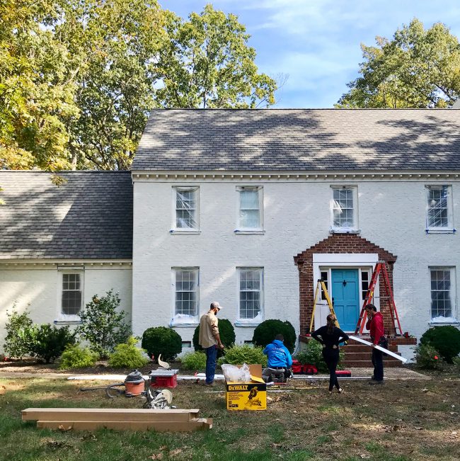 contractors working to rebuilt portico of brick house during painting